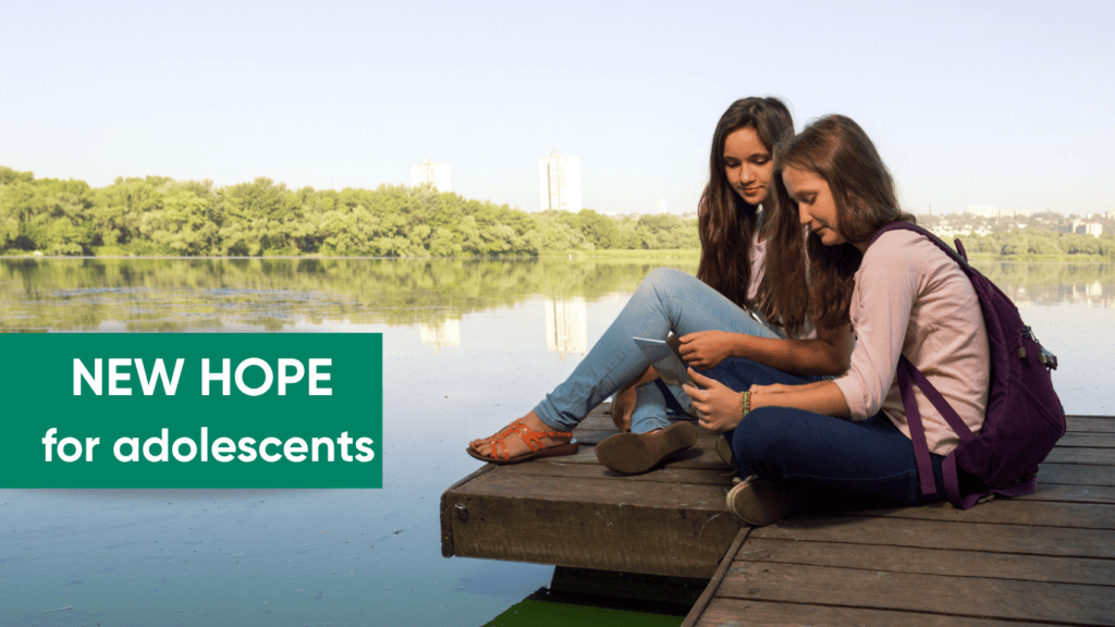 Two teenagers sitting on a dock at a lake